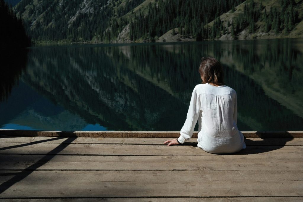 a woman sitting on a dock looking at a lake